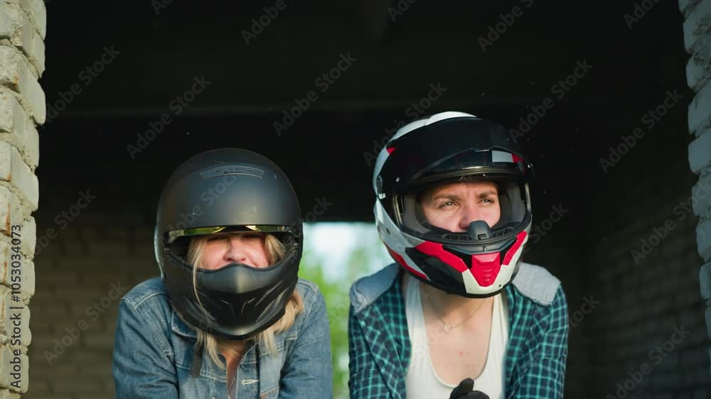 Two women wearing helmets are leaning forward, the woman on the right seems to be looking at someone, while the other looks into the distance, both with intense expressions. Two women wearing helmets are leaning forward, the woman on the right seems to be looking at someone, while the other looks into the distance, both with intense expressions.