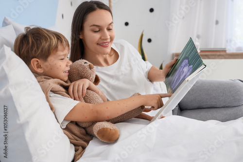 Fotografie Mother reading book to her little son ill with chickenpox in bedroom