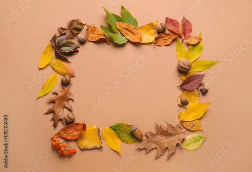 Frame made of beautiful autumn leaves, rowan berries and acorns on color background