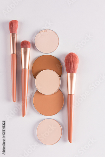 Beautiful cosmetic background with a set of beige makeup brushes and some round blocks, a refill compact powder in various tones. vertical. flat lay