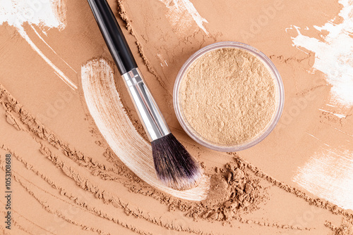 A cosmetic jar of loose powder in a natural tone on a powder sample, a brush stroke and makeup brush. top view. powder texture. decorative cosmetics.