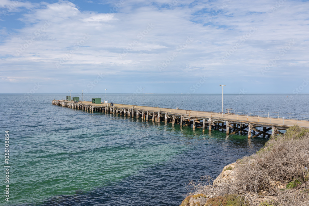 An old commercial jetty stretching out into the calm aquamarine waters of the Southern Ocean under a cloudy sky at Edithburgh on the Yorke Peninsula in South Australia. An old commercial jetty stretching out into the calm aquamarine waters of the Southern Ocean under a cloudy sky at Edithburgh on the Yorke Peninsula in South Australia.