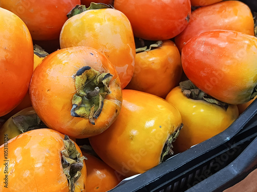 A persimmon with leaves lies in a box in close-up. Harvesting. Selling organic fruits on the market is a concept. The background for the advertisement, the place for the text. photo