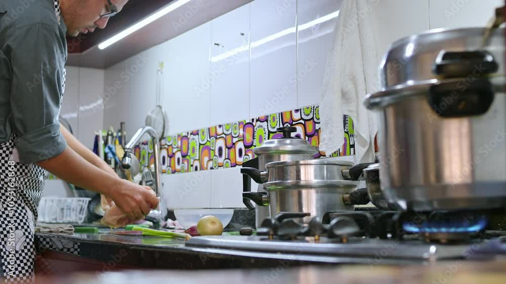 Young single man cooking chiken at home kitchen Young single man cooking chiken at home kitchen