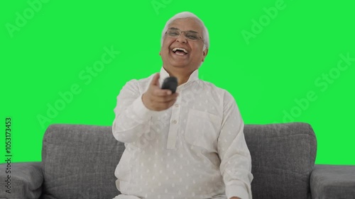 Happy Indian old man watching TV and laughing Green screen