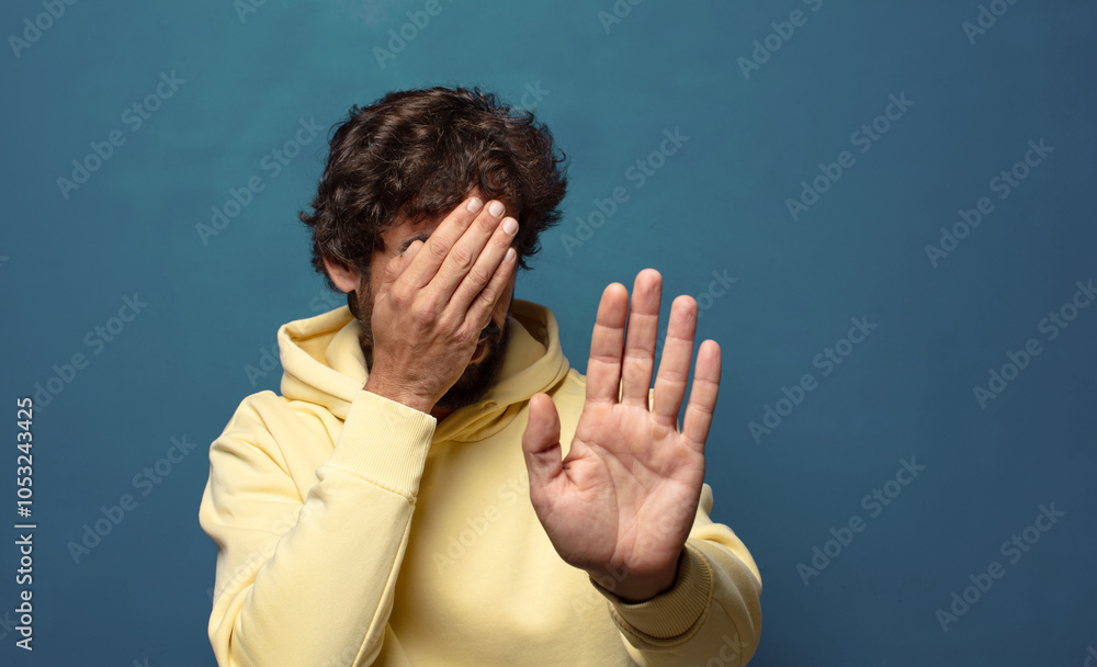 covering face with hand and putting other hand up front to stop camera ...