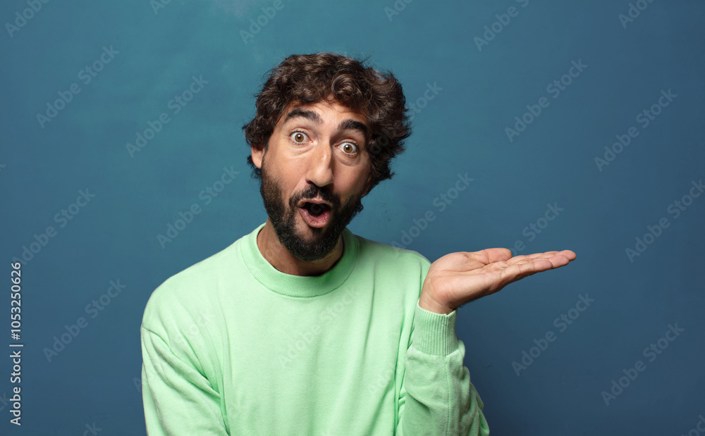Naklejka premium looking surprised and shocked, with jaw dropped holding an object with an open hand on the side