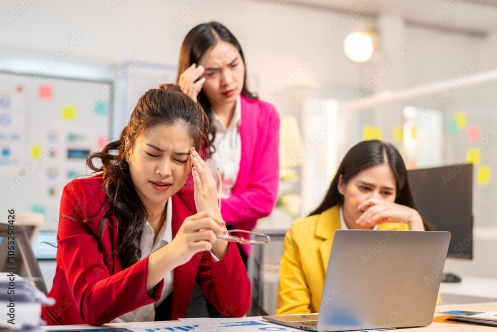 Three women in office, one of them is wearing a red jacket Three women in office, one of them is wearing a red jacket