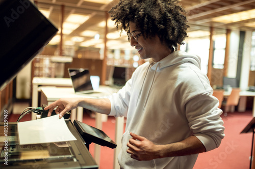 Young man making copies on xerox in the library