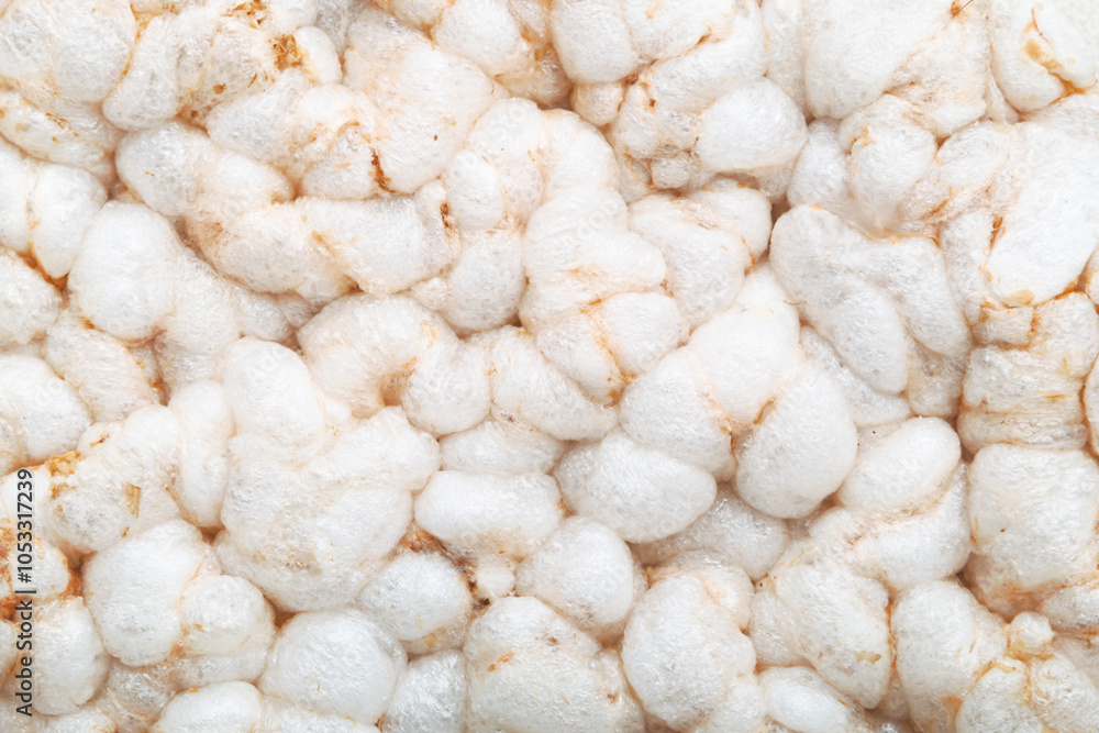 Close-up view of a cluster of white rice cakes or rice crispbreads. The unique texture of the puffed rice grains, with each grain appearing soft, airy, and lightly browned in some areas. Close-up view of a cluster of white rice cakes or rice crispbreads. The unique texture of the puffed rice grains, with each grain appearing soft, airy, and lightly browned in some areas.