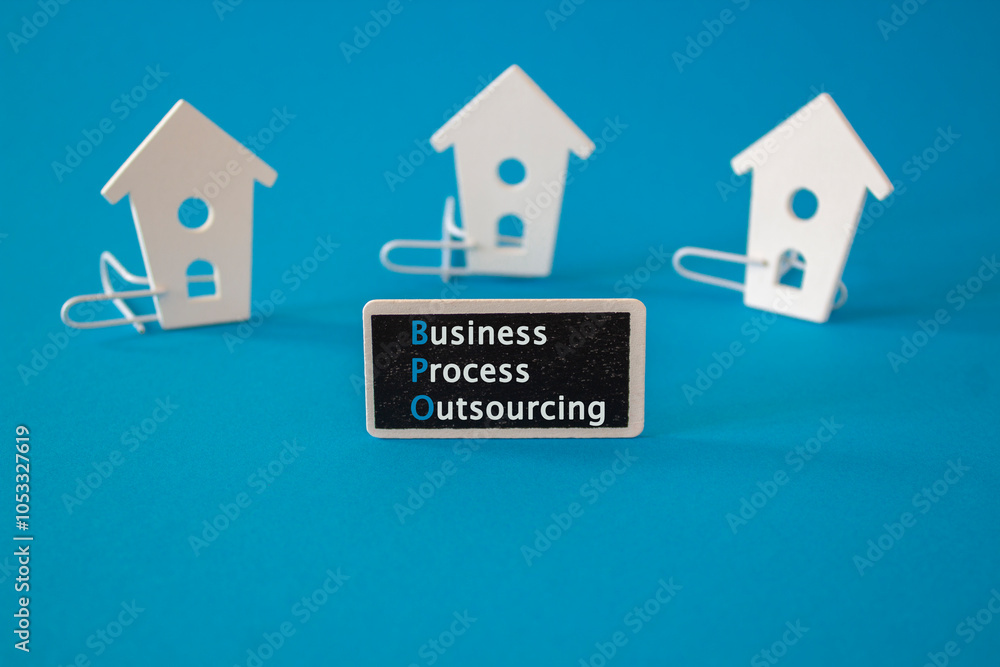 Business Process Outsourcing symbol. Wooden houses stay next to a wooden black board with the words Business Process Outsourcing. Beautiful blue background. Business concept.