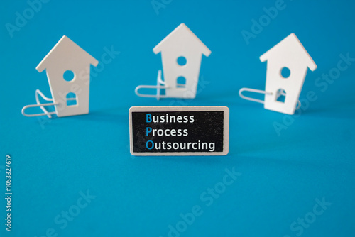 Obraz na płótnie Business Process Outsourcing symbol. Wooden houses stay next to a wooden black board with the words Business Process Outsourcing. Beautiful blue background. Business concept. w salonie