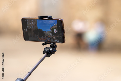 Smartphone on selfie stick recording outdoor scene in urban setting