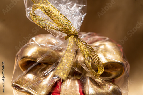 decorative golden ribbon of red square gift box cut out also with golden ribbon wrapped in transparent foil on softly illuminated golden background photo