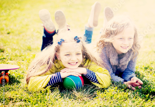 Two girls lie on grass photo