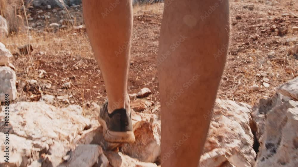 A tourist walks along a rocky path near the seashore. Close-up of a man legs A tourist walks along a rocky path near the seashore. Close-up of a man legs