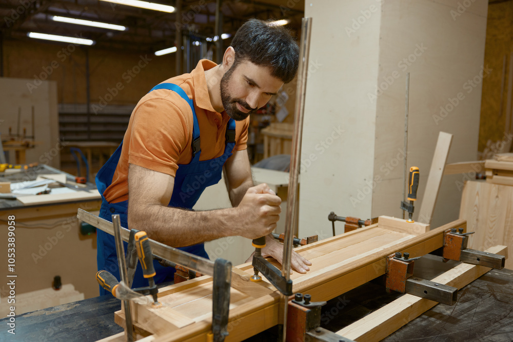 Carpenter working at workbench with clamps that allow to fix wooden workpiece Carpenter working at workbench with clamps that allow to fix wooden workpiece