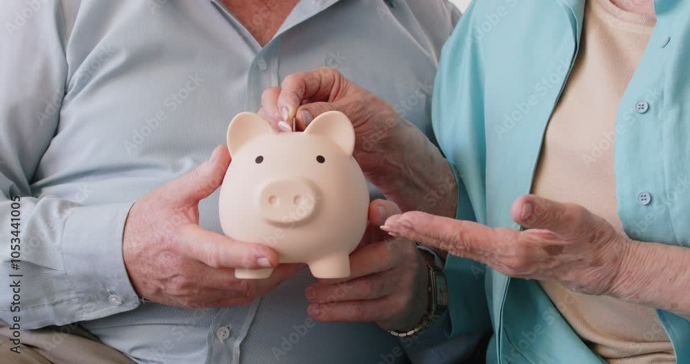 Elderly couple puts coin in piggy bank together, nurturing joint ...