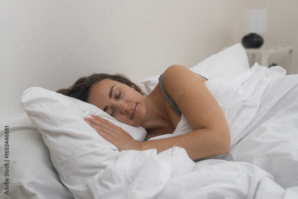 Serenely asleep, a young lady rests under a white blanket on her comfortable orthopedic mattress in a well-lit bedroom. Serenely asleep, a young lady rests under a white blanket on her comfortable orthopedic mattress in a well-lit bedroom.