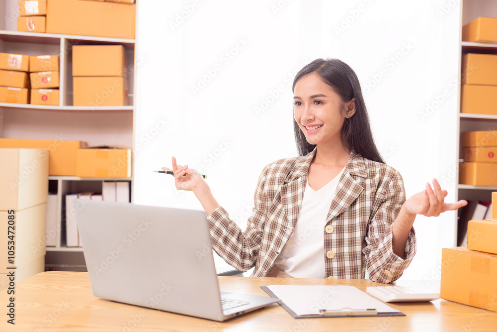Small business startup, SME owner, Asian woman checking online orders, selling products at home, working with boxes and laptop, freelancer Small business startup, SME owner, Asian woman checking online orders, selling products at home, working with boxes and laptop, freelancer