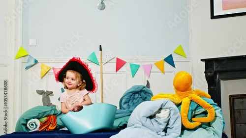 Young child in a pirate hat surrounded by plush toys and bunting photo