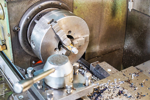 A precision lathe operates in a bustling factory, shaping metal components during a busy production shift filled with activity photo