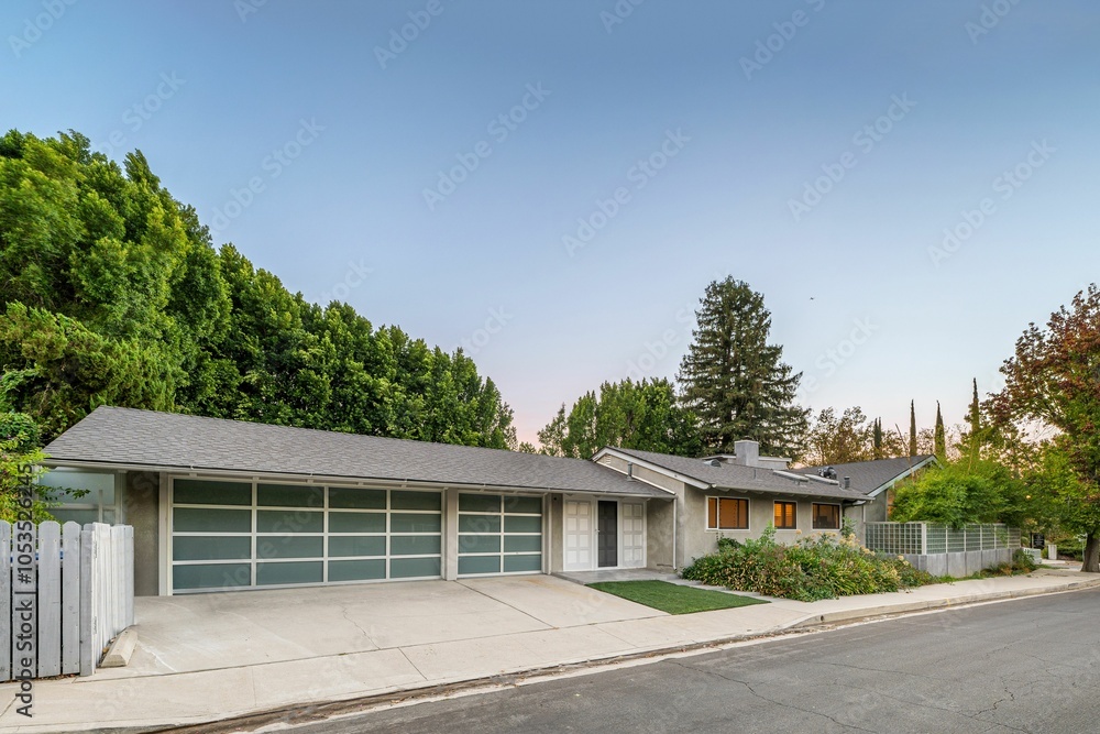 Modern suburban house with a spacious driveway, surrounded by lush greenery Modern suburban house with a spacious driveway, surrounded by lush greenery
