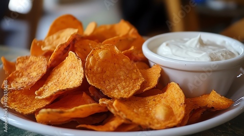 Delicious plate of crunchy orange sweet potato chips served with a creamy dipping sauce. photo