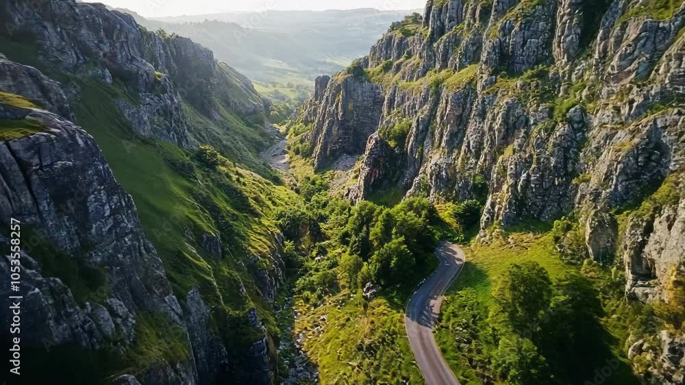 A winding road cuts through a lush valley in the English countryside, surrounded by towering cliffs A winding road cuts through a lush valley in the English countryside, surrounded by towering cliffs