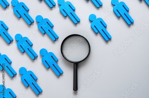 A magnifying glass with a row of blue figures. Copy space for text. Selection, focus, attention, and finding the right person concept. photo