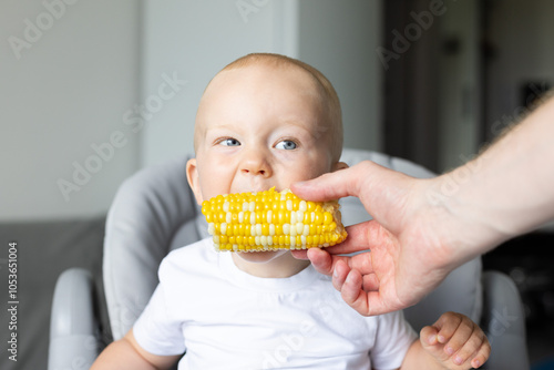 Father feeding the baby with sweet corn cob. photo