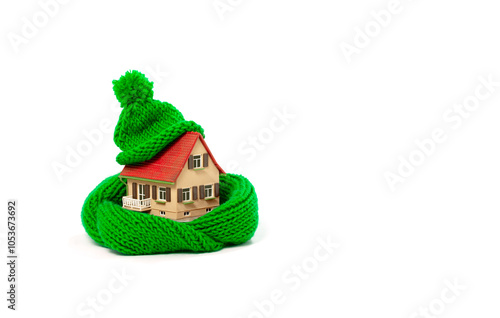 thermal insulation of  buildings saves energy and heating costs: old model house with green scarf and hat, white background