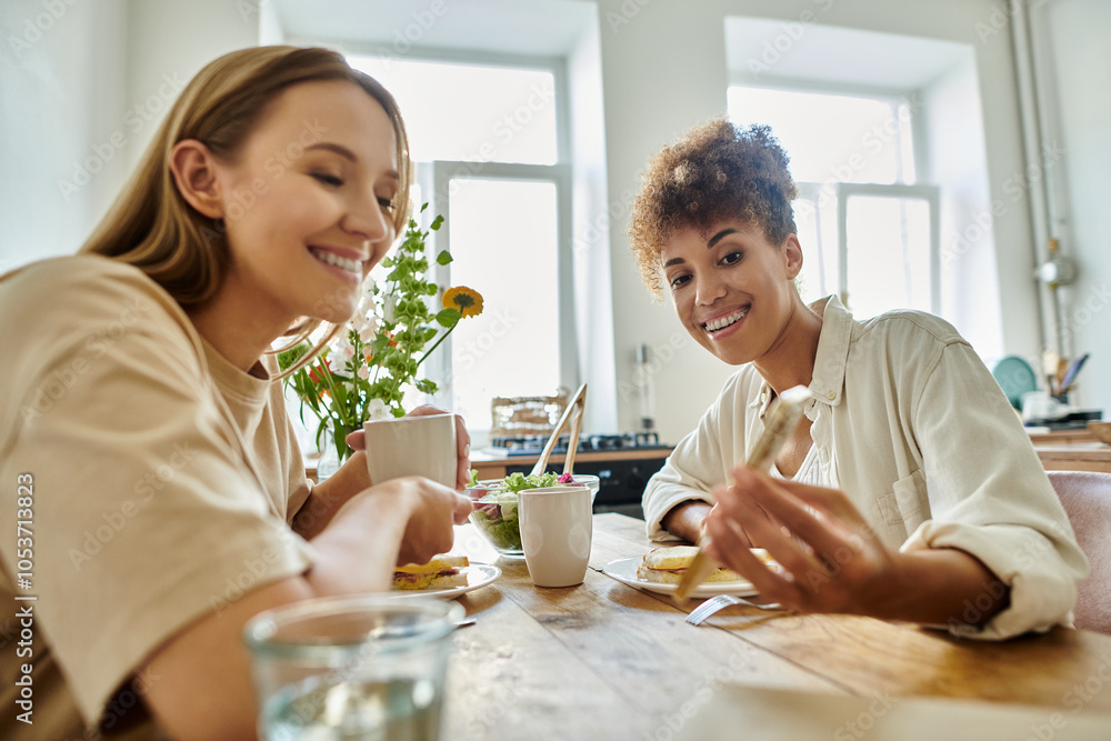 Two partners share laughter and delicious food in a sunlit kitchen. Two partners share laughter and delicious food in a sunlit kitchen.