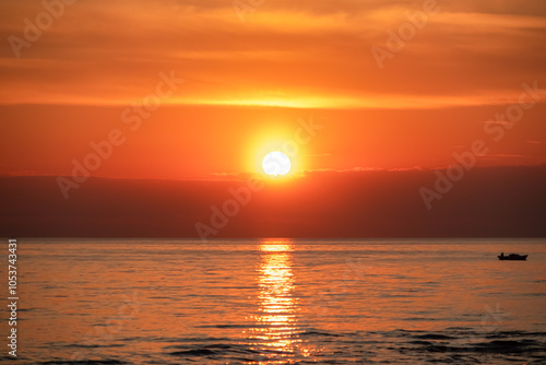 Fototapeta Naklejka Na Ścianę i Meble -  Breathtaking fiery sunset over calm Adriatic Mediterranean sea. Scenic view from coastline of Karigador, Istria peninsula, Croatia. Golden glow across sky and water. Silhouette of rocky beach