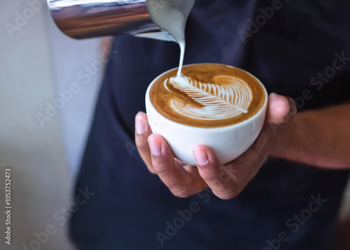 Taza en manos de un barista mientras hace un dibujo en el café recien servido. Es latte Art photo