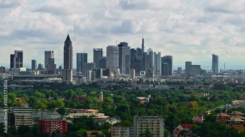 tele shot Drone video with zoom lens compressed of Frankfurt's skyline on a partly cloudy day. modern skyscrapers, historic buildings, and the dynamic cityscape under a bright, mixed sky  move left photo