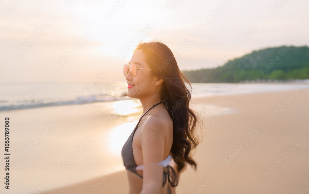 A woman in a bikini walks along a sandy beach with the sunset behind her. A woman in a bikini walks along a sandy beach with the sunset behind her.