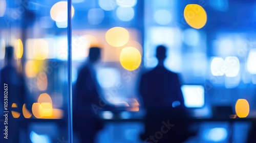 Blurred businessmen in an office setting with a computer featuring a shallow depth of field and an abstract background
