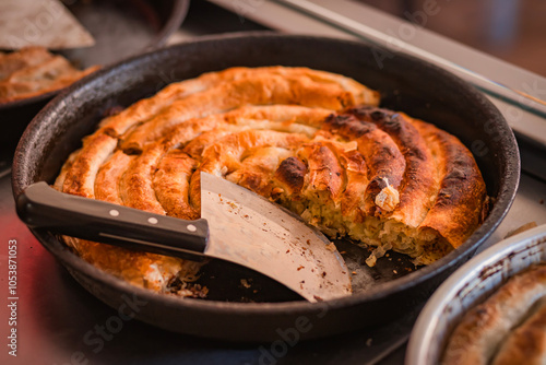  Close-up of Spiral-shaped baked pastry in a pan pita or burek, with a golden-brown crust. photo