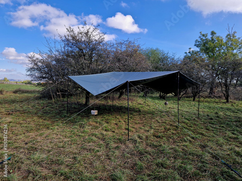 a tourist shelter on a boat made of taut ropes and a piece of sail. the tent without sides serves as protection against bad weather in the goat pasture