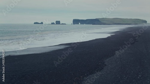 Experience the spectacular beauty of Icelands black sand beach with captivating aerial drone footage capturing powerful waves crashing against the coast amidst stunning natural scenery
