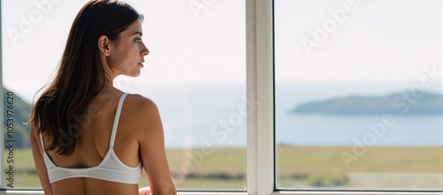 Young woman poses suggestively near a window in lingerie photo