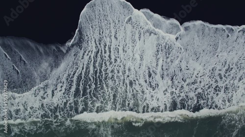 Experience the spectacular beauty of Icelands black sand beach with captivating aerial drone footage capturing powerful waves crashing against the coast amidst stunning natural scenery