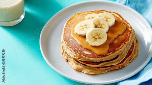 A stack of fluffy pancakes topped with sliced banana and a drizzle of peanut butter.