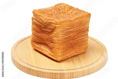 Korean tissue bread—a tall stack of ultra-thin, square bread layers with a buttery croissant-like dough. Photographed on a wooden base with a white background.