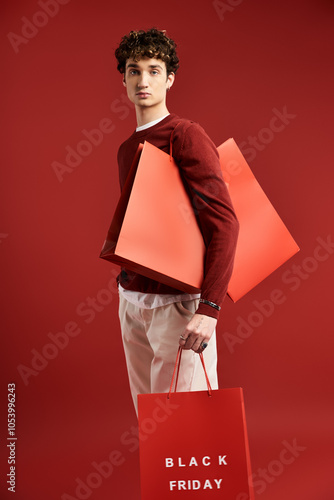 A handsome young man proudly holds shopping bags, capturing the thrill of Black Friday in a studio space. photo