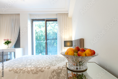 Fruits on the Table and Blurry Luxurious Master Home Bedroom Interior, Modern House, BeautifuI interior, King Size Bed. Window to Balcony. Flowers on the Table photo