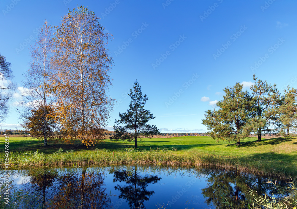 Beautiful autumn panorama on the shore of Kisezers lake with green lawns on a sunny autumn day in Riga. Latvia. Beautiful autumn panorama on the shore of Kisezers lake with green lawns on a sunny autumn day in Riga. Latvia.