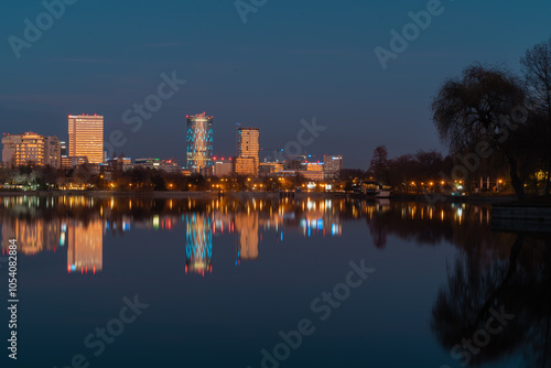 The lake in the Herastrau park at dusk. Night landscape with Skyscrapers with lit lights reflecting in the water at night
