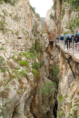 Province of Malaga, Andalusia, southern Spain. Unidentifiable visitors wearing helmets against falling stones on vertical rock faces on the Kings Walkway or El Caminito del Rey. photo